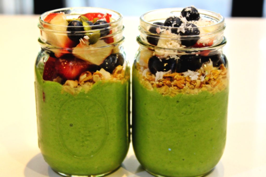 organic green smoothies in mason jars with granola banana and blueberries on top