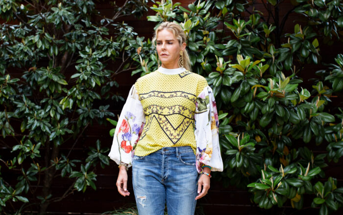 woman wearing yellow big sleeve Ganni blouse, ripped boyfriend jeans in front of magnolia trees